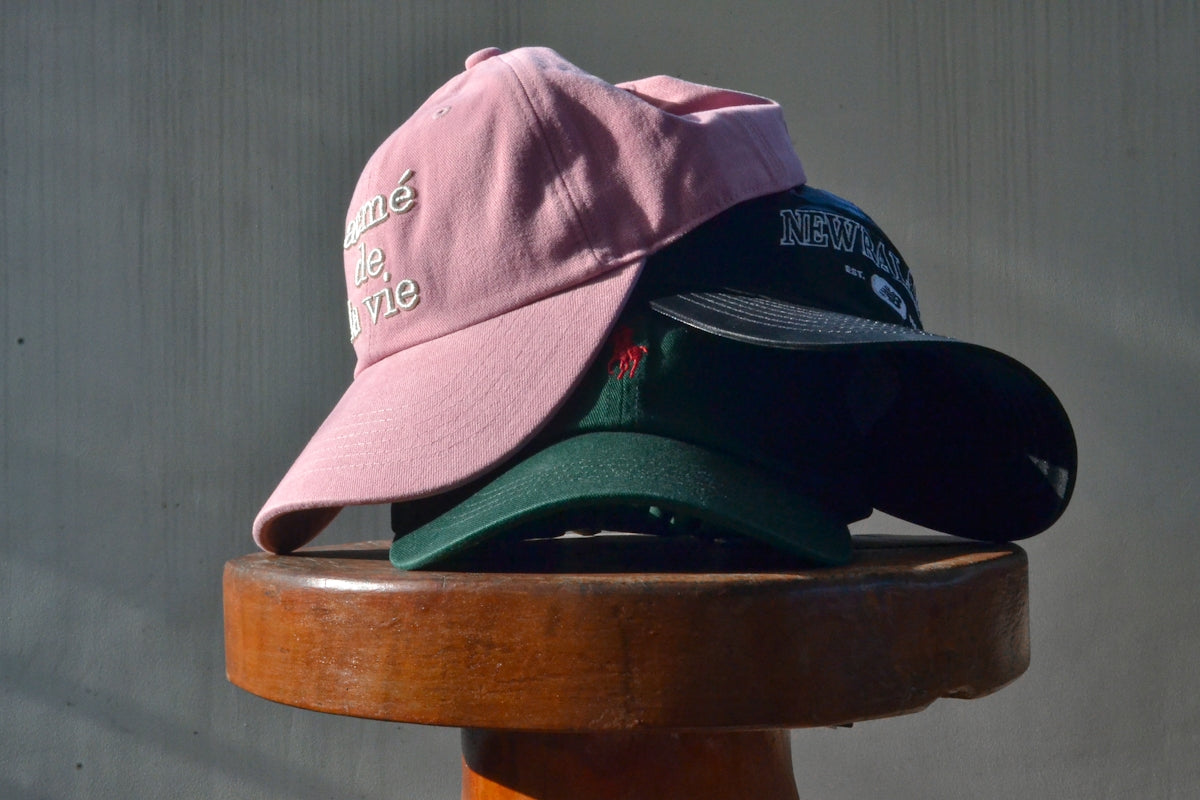 Three baseball caps stacked on a stool
